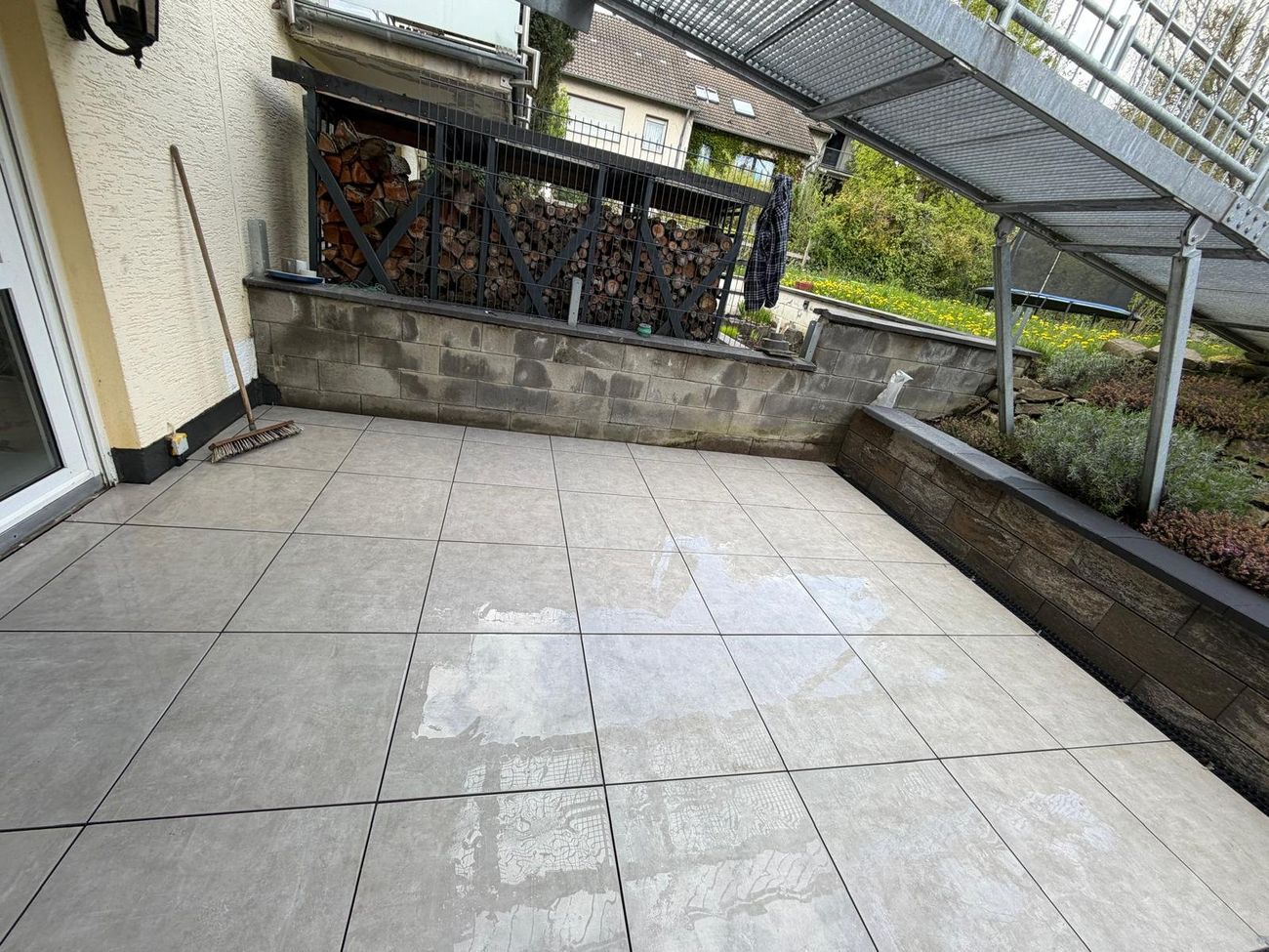 Terrasse mit grauen Feinsteinzeug-Platten an einem Wohnhaus
